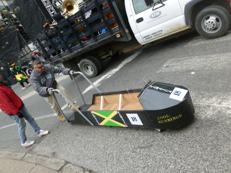 a woman holding onto the back of a vehicle pulling it down a street