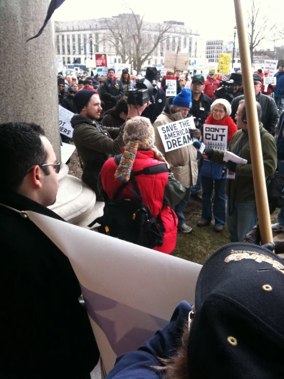 a large crowd of people holding signs near a sidewalk