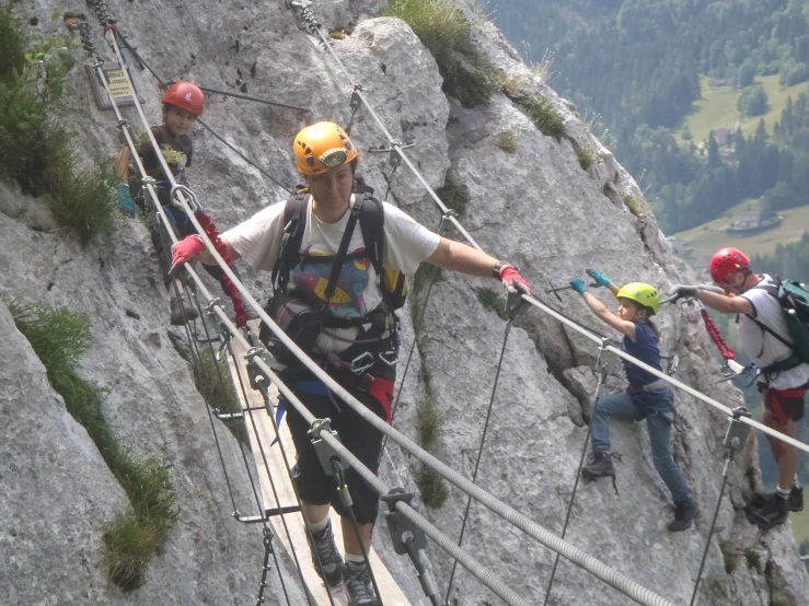 the man is walking along a rope line above the mountain