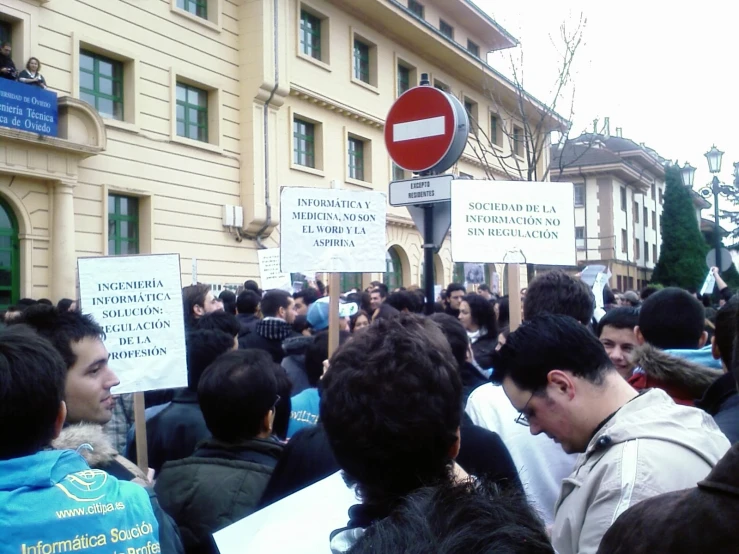 many people are holding up signs in front of a building
