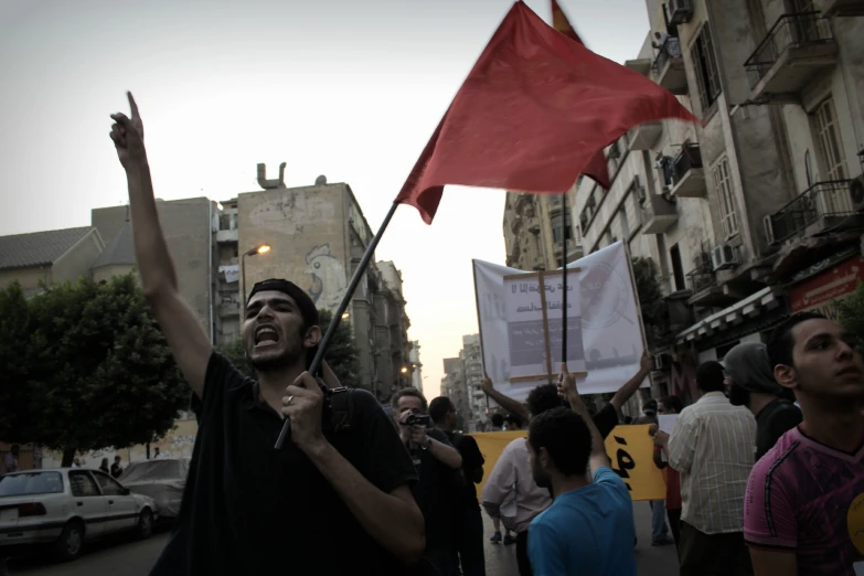 a man on a street with protest signs and a flag