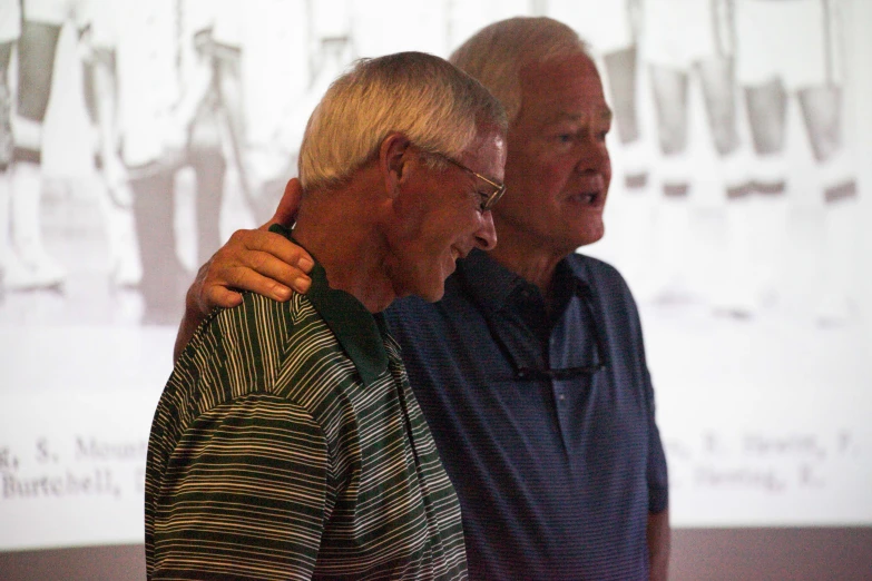 two men standing next to each other in front of a projection screen