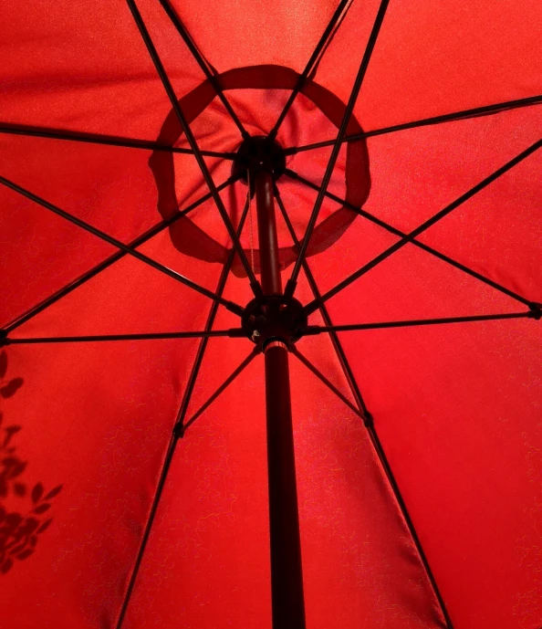 a red umbrella with tree shadow on it