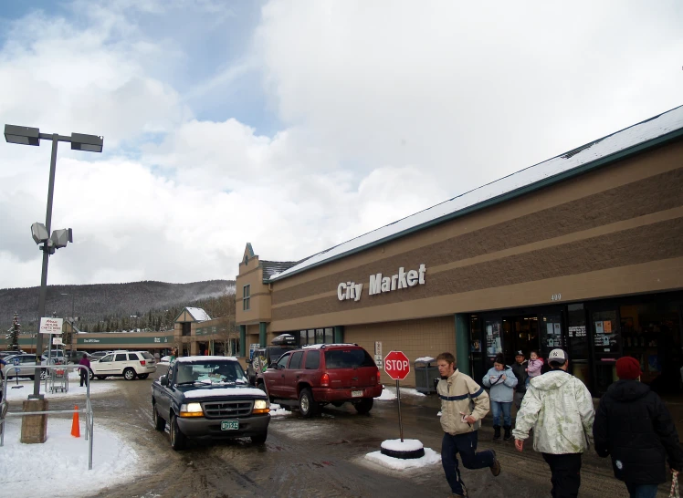 cars are parked outside a building that is currently a city market