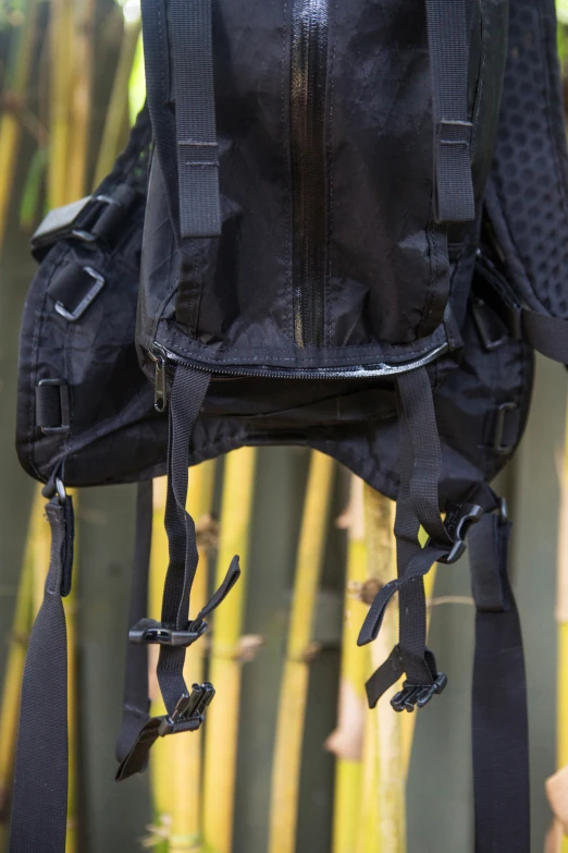 black backpacks tied to bamboo and hanging from hooks