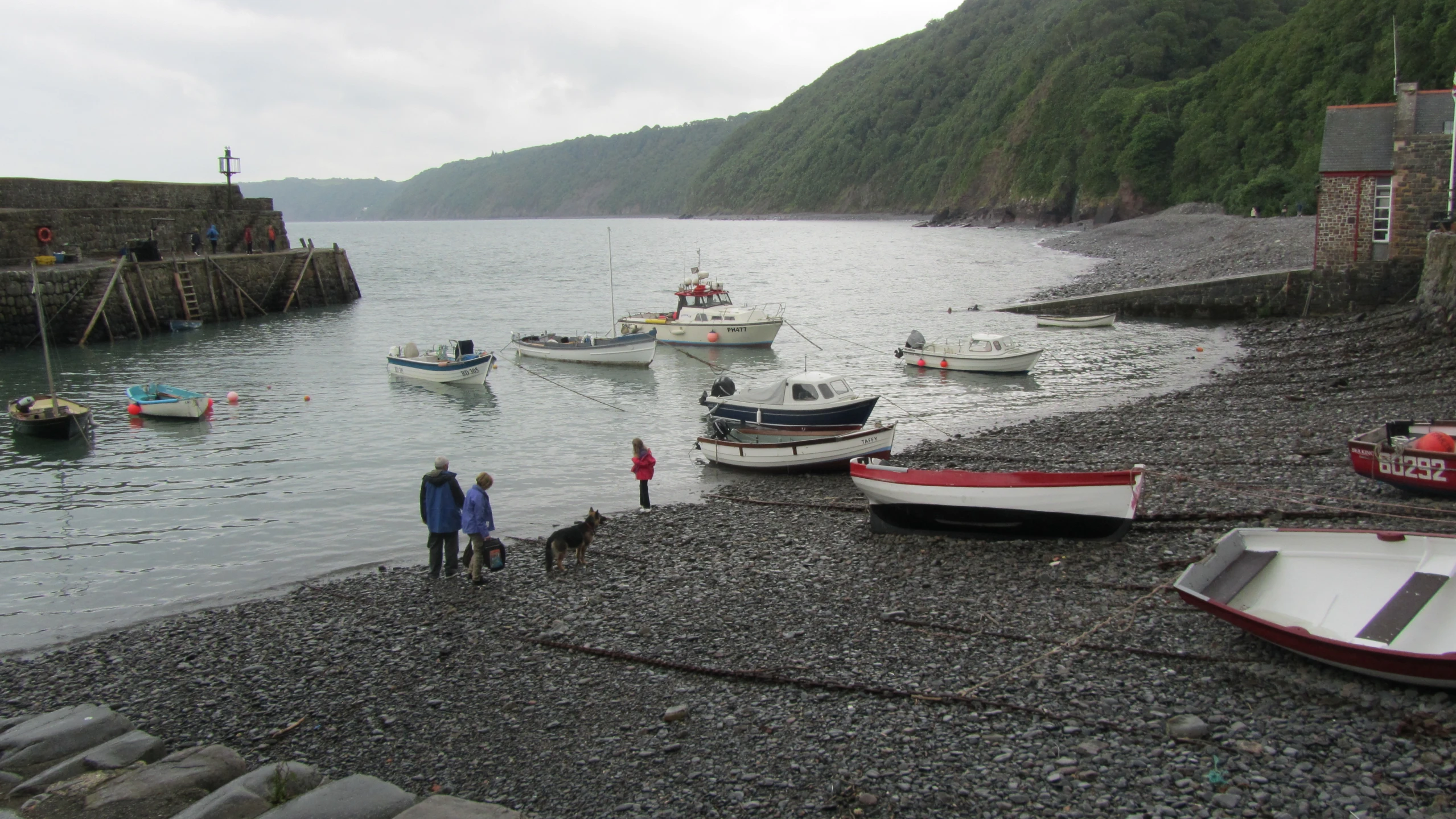 several small boats in water near shore with people standing on it