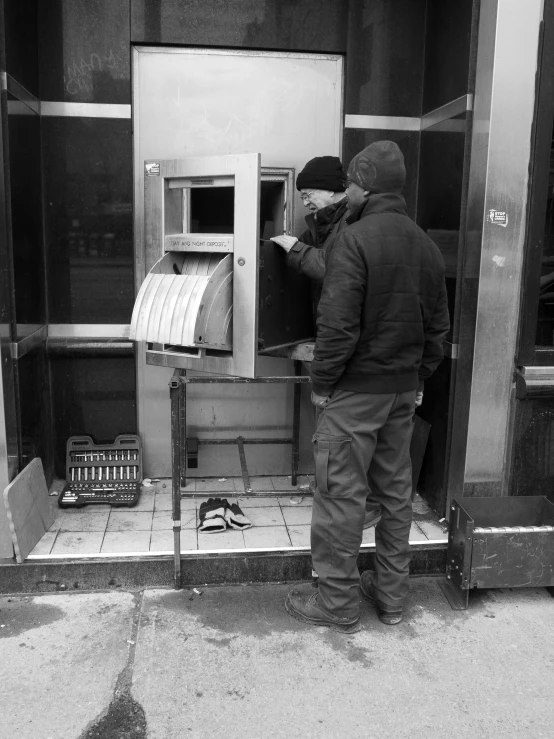 two men are looking at a machine on a sidewalk