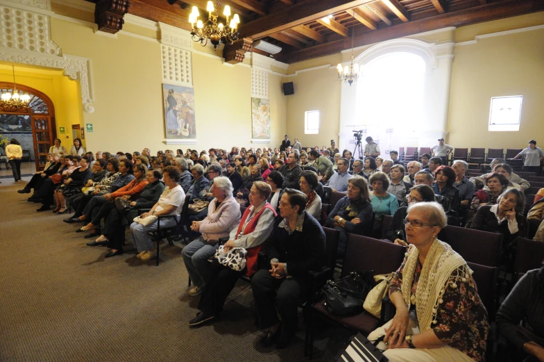 a large group of people in an auditorium with their hands together