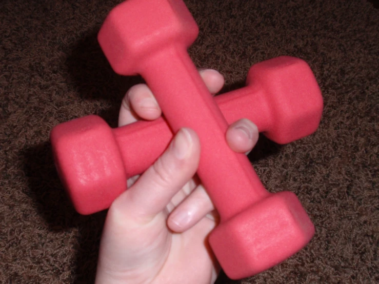a person holds a pink plastic toy for weights