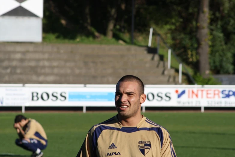 a man with a referees yellow jacket and a soccer ball on a field