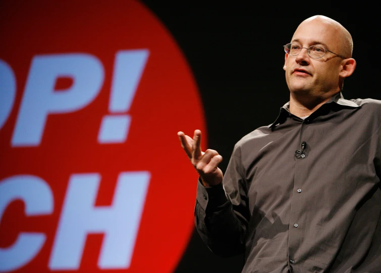 a bald headed man making gestures at an event