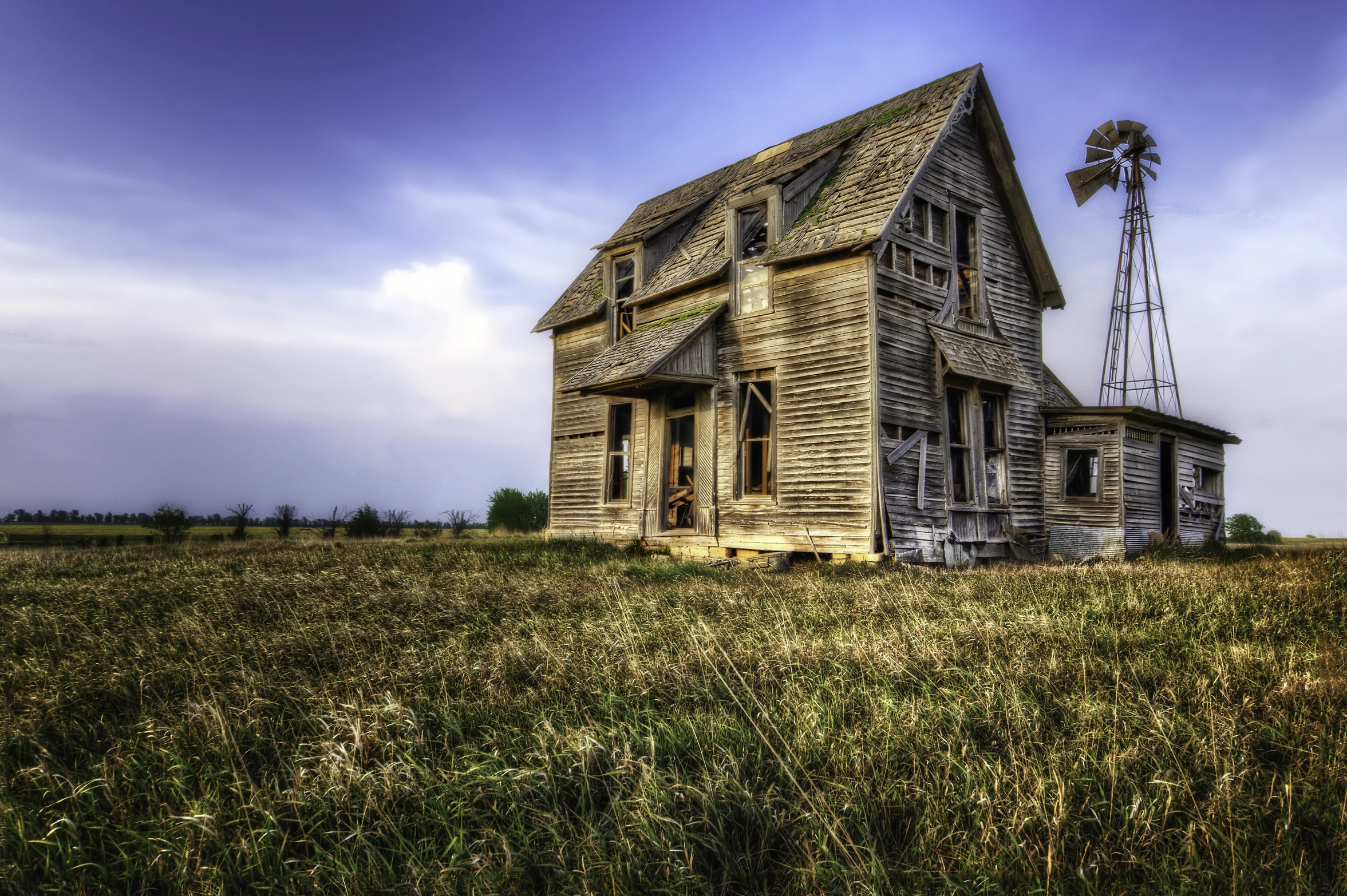 an old abandoned house in a field of tall grass