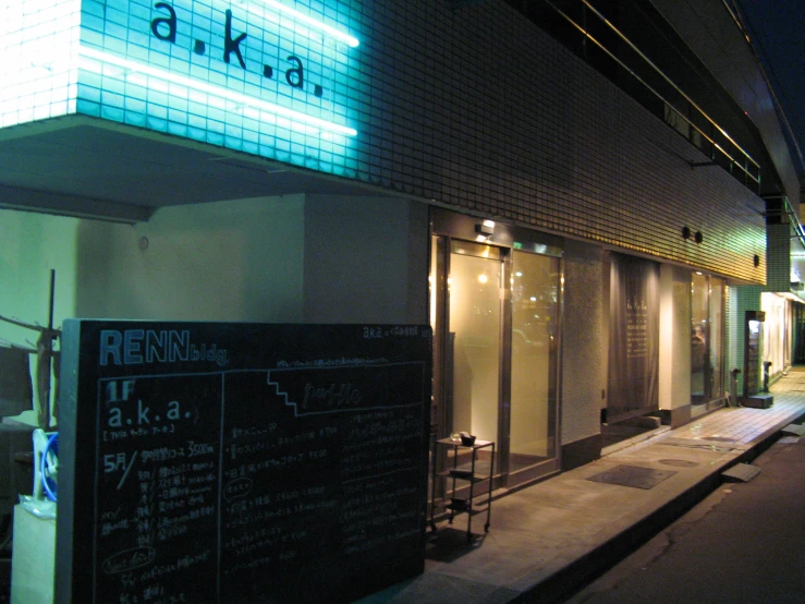 sidewalk outside the building with lit up neon signs