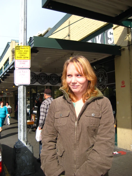 the woman stands under a stop sign on the side walk