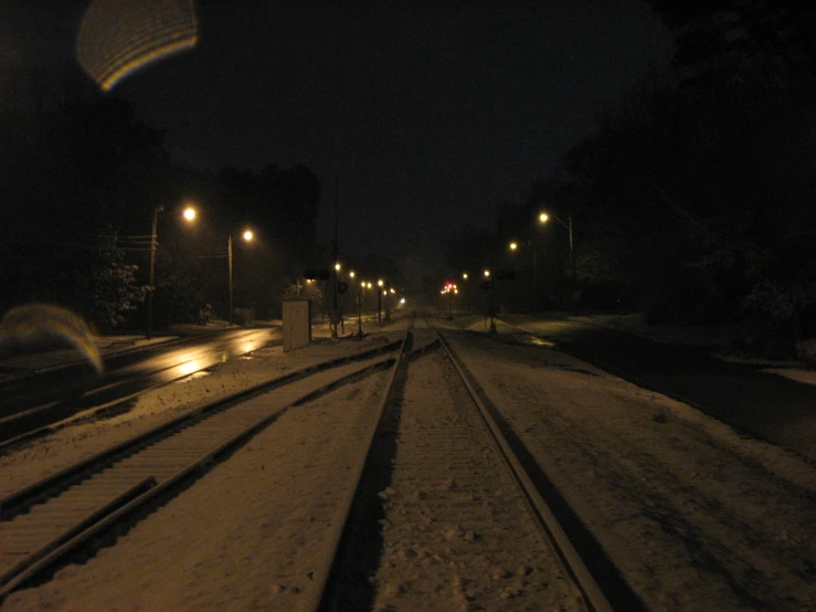 a train track at night with light bulbs on the side