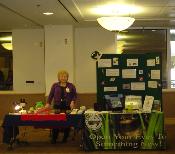 a woman behind a table selling her green items