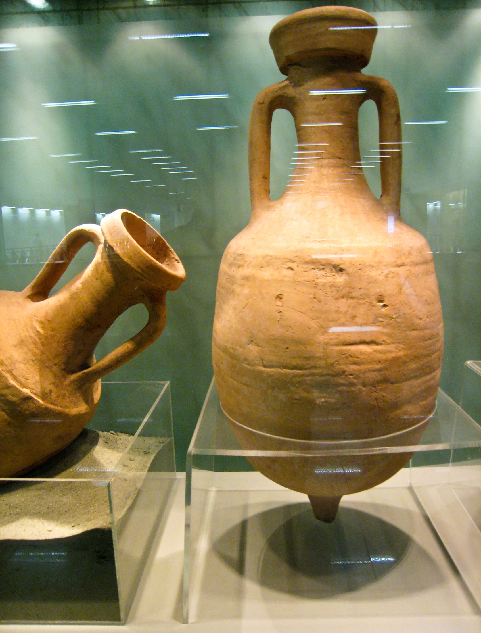 two ancient clay urns are in clear display cases