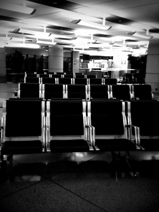 several empty seats in an airport terminal with empty wall