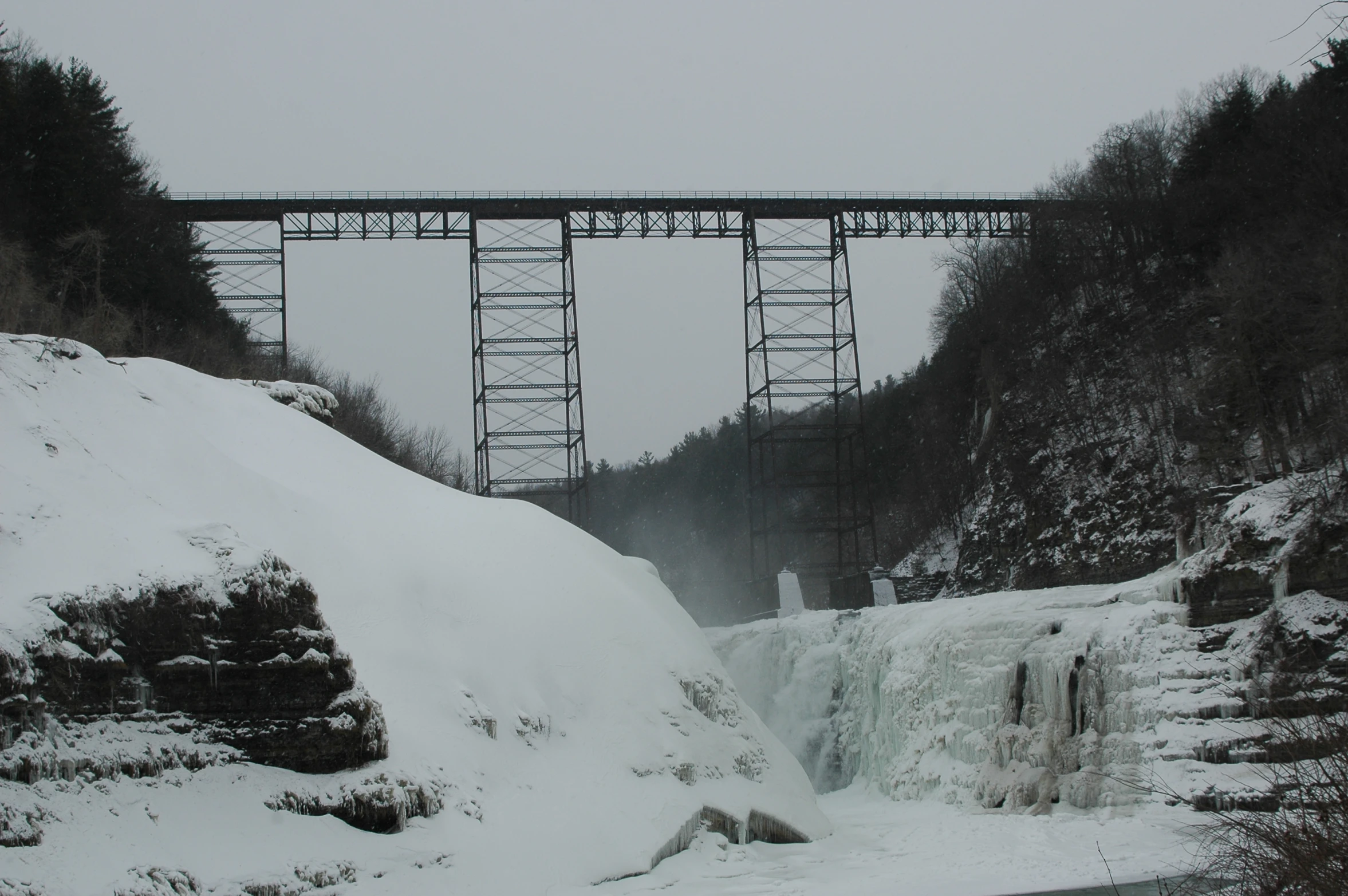 an icy river under a bridge on top of a mountain