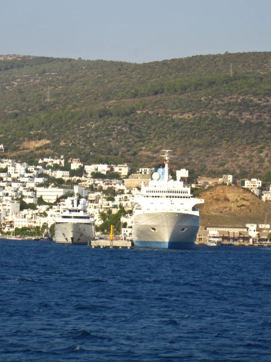 a big cruise ship sitting on the water with a large town in the background