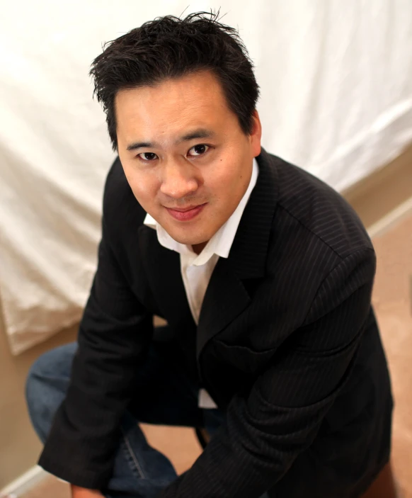 a man sitting on the ground next to a white backdrop
