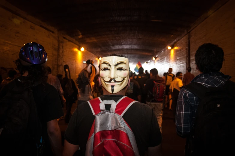 man with mask standing near subway entrance while wearing backpack