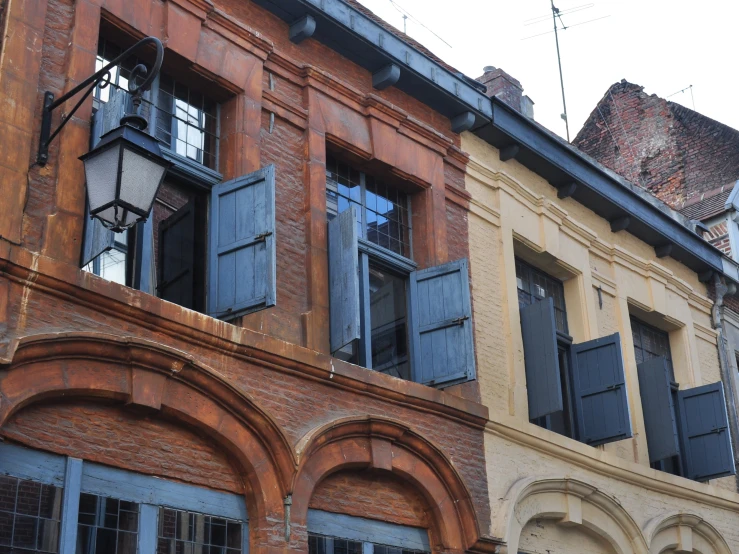 an old building with closed windows and an iron clock on the front