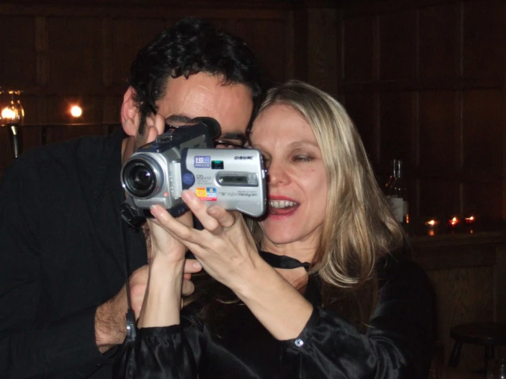 a man and woman standing next to each other taking pictures