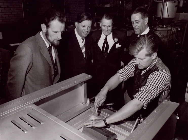 four men in suits are opening a large metal chest