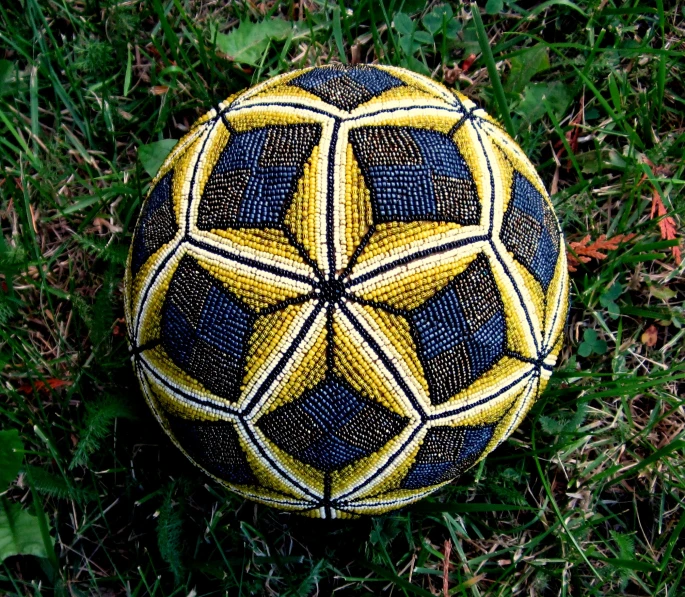 the view from above shows a yellow and black dotted, patchwork - woven soccer ball