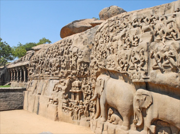 a stone wall covered with carvings depicting elephants