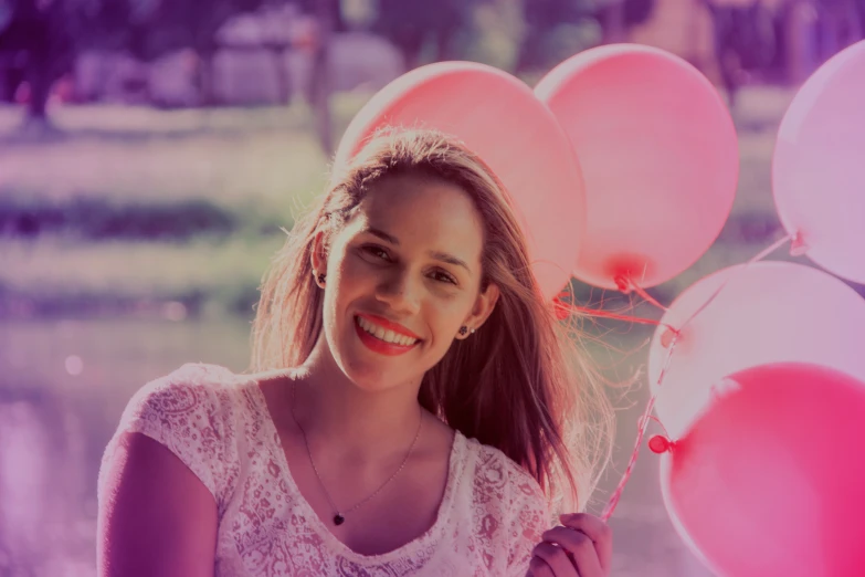 woman wearing a white shirt holding up a bunch of balloons