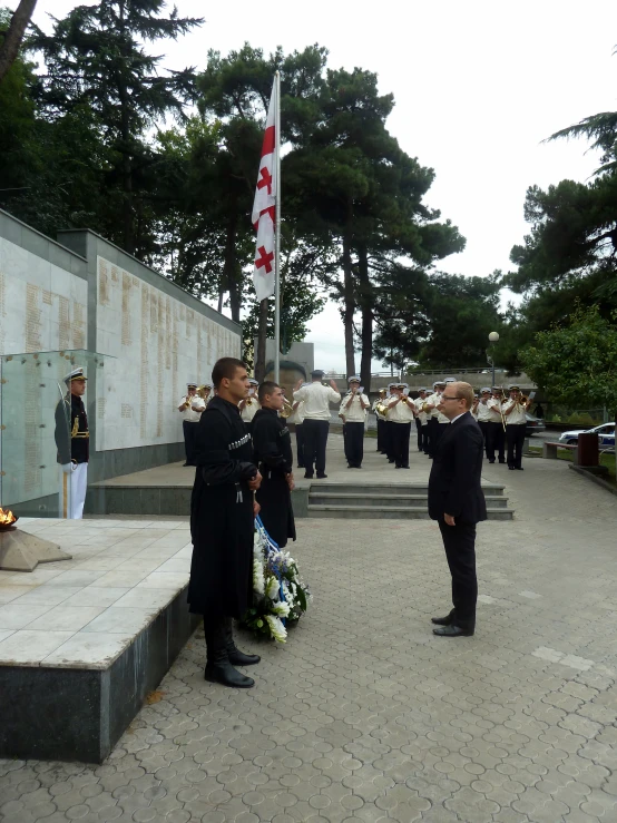 the color guard in uniform stand near wreaths with american flags in the background