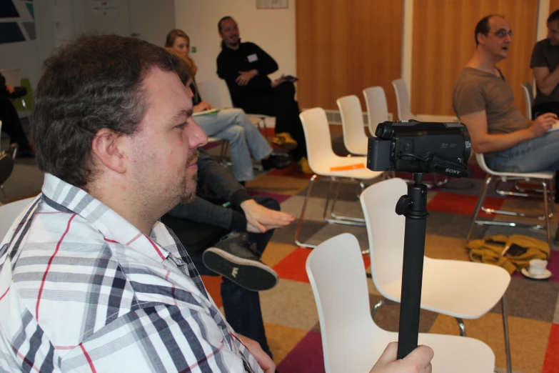 several people are sitting on chairs in a room with video camera