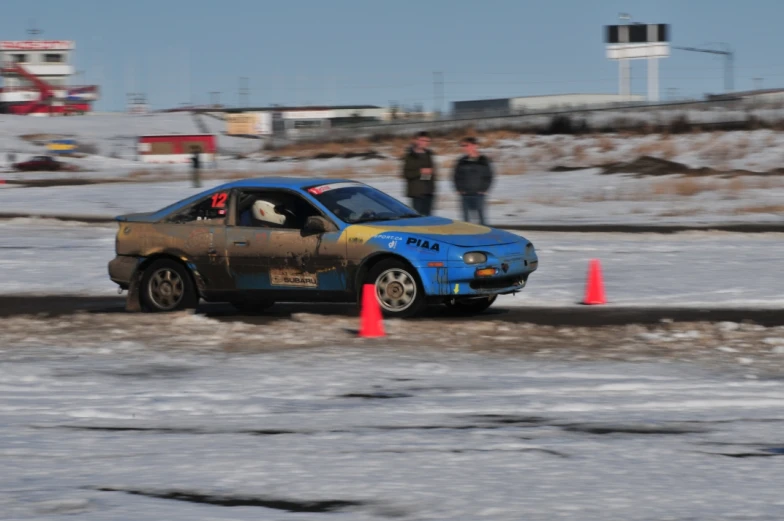 an automobile has been stopped in a snow covered area with orange cones