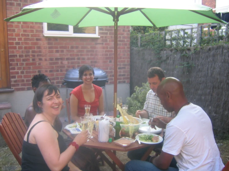 a family is sitting around the patio to eat lunch