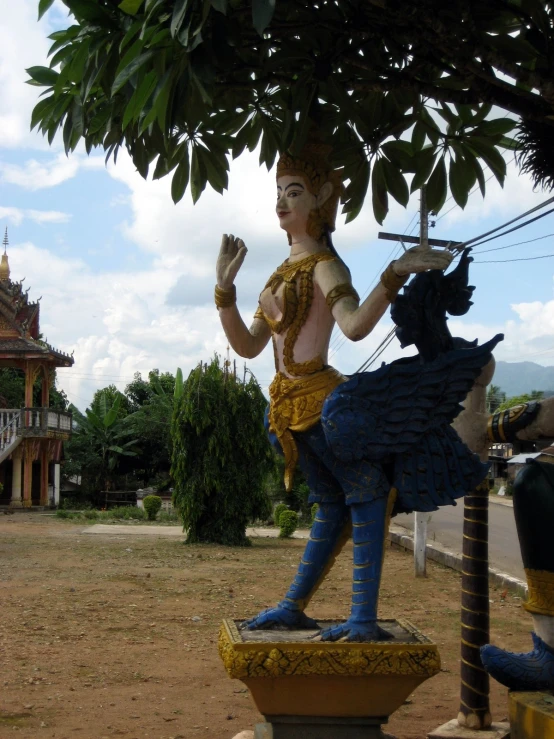 a statue of a man holding a sword under a tree