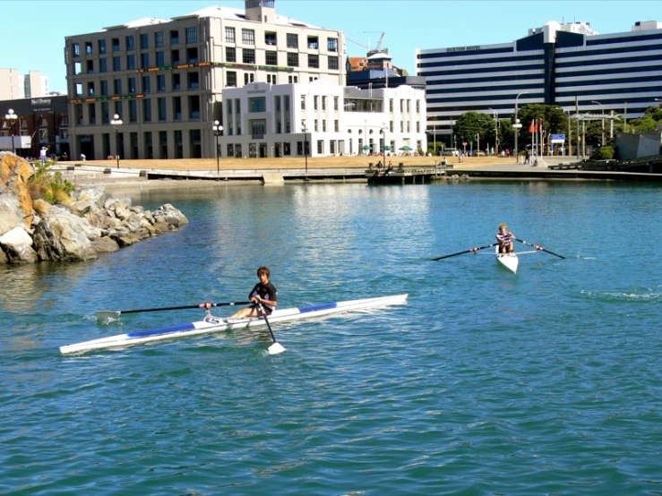 some women rowing on water in a city