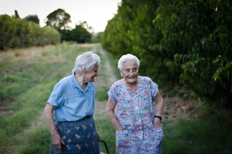 an older couple standing near each other by some bushes