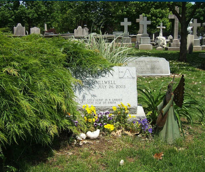 a grave in a grass field with flowers next to it