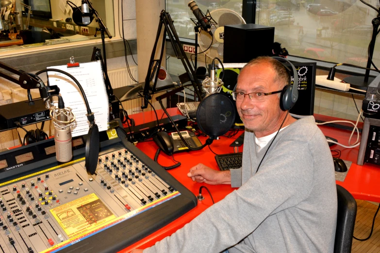 a smiling man is sitting in front of sound board in a recording studio