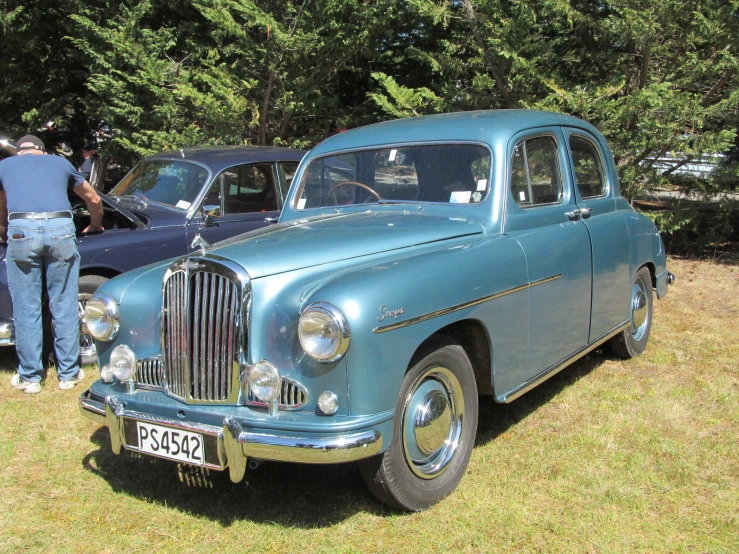 two older cars parked in a grass field