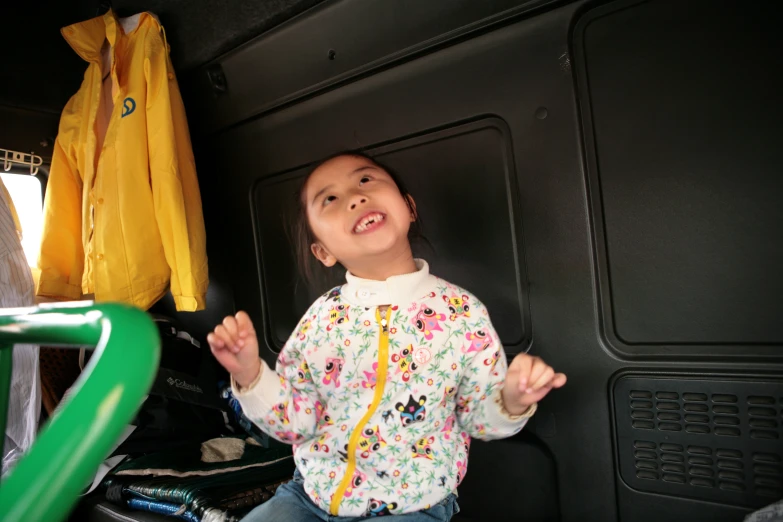 little girl posing in her van, holding out one hand