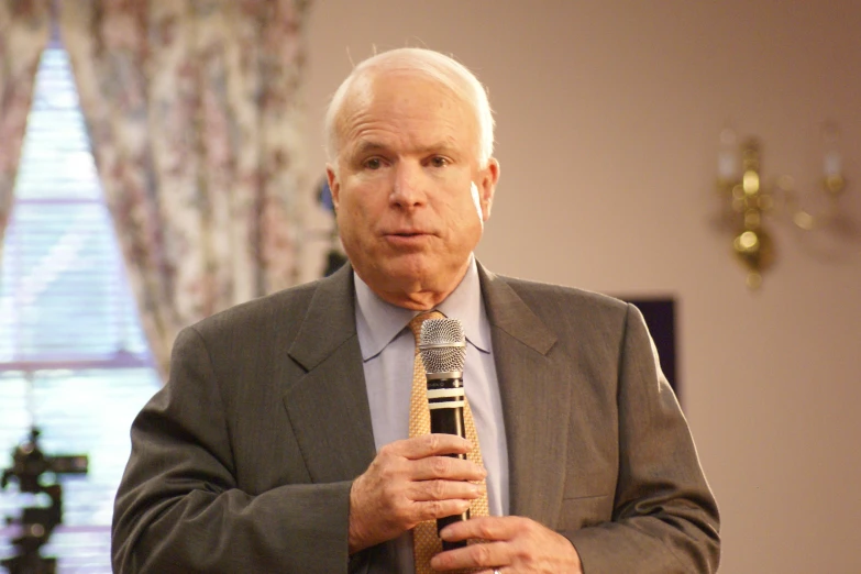 man holding a microphone while standing in front of a mirror