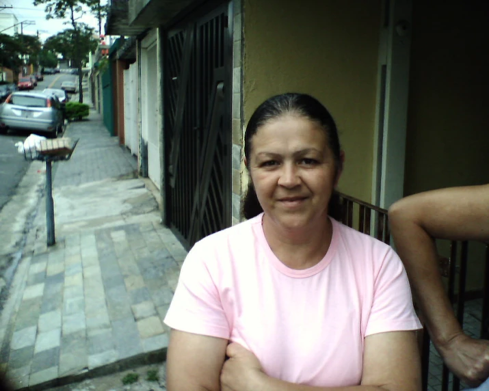 a woman in a pink shirt smiles in front of a building