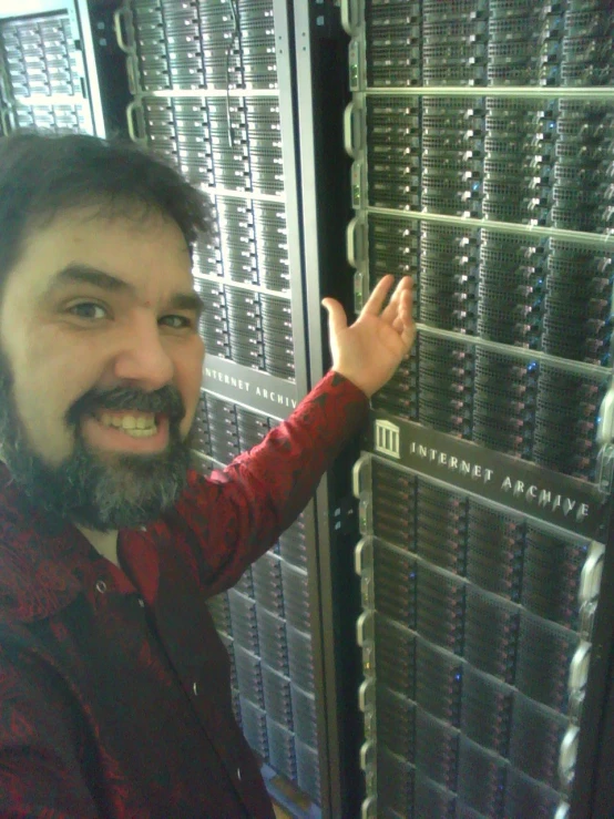 a man pointing at rows of servers on the wall
