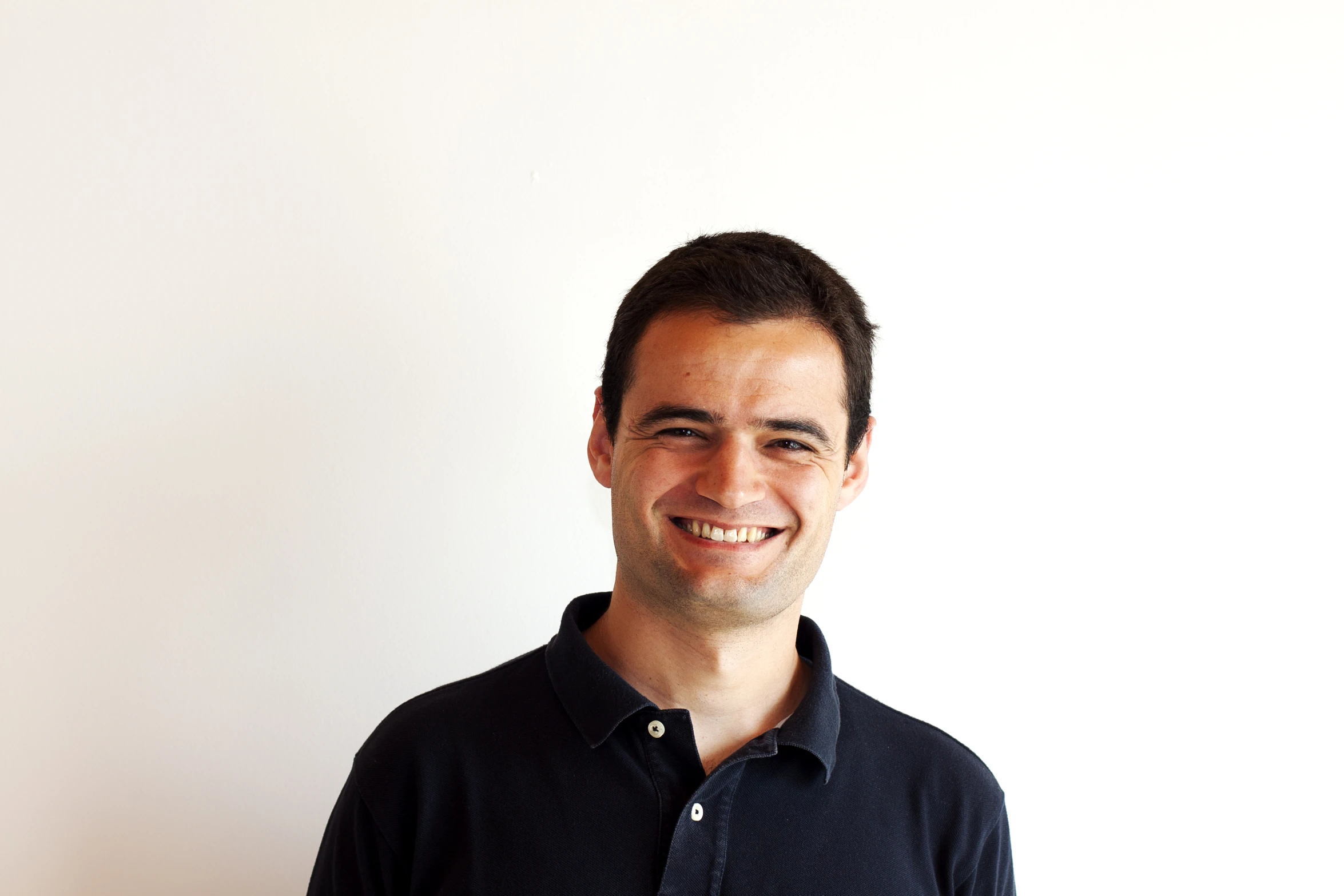 a man in a polo shirt smiles at the camera