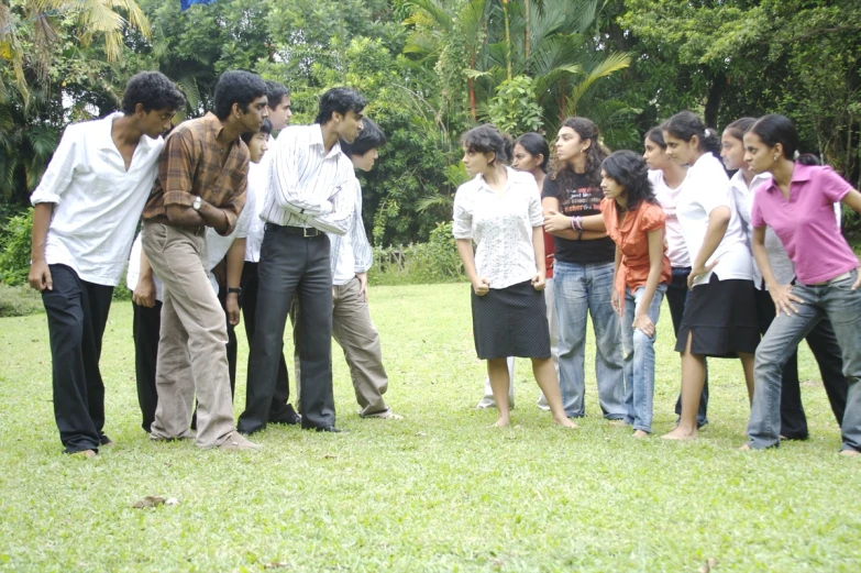 a group of people stand on grass in front of trees