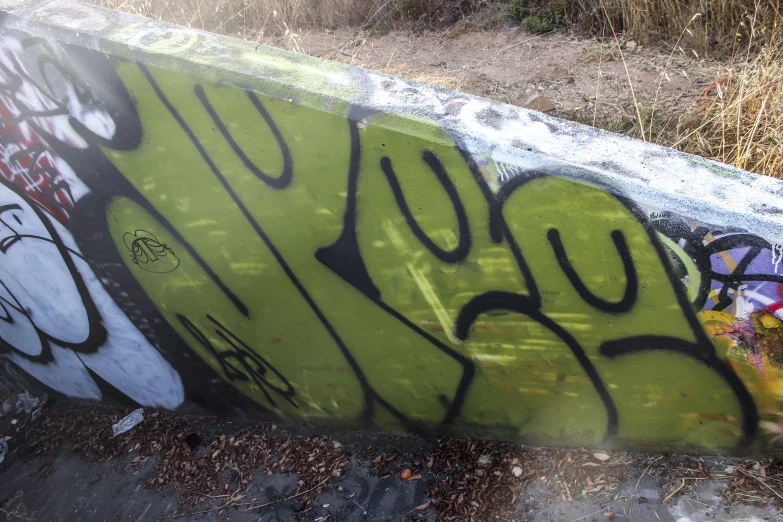 graffiti on the side of a concrete ledge with a grassy area
