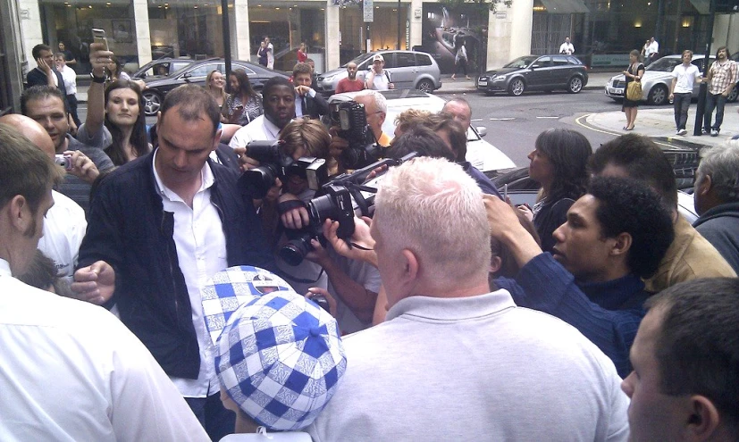 a man is surrounded by a crowd of people and filming